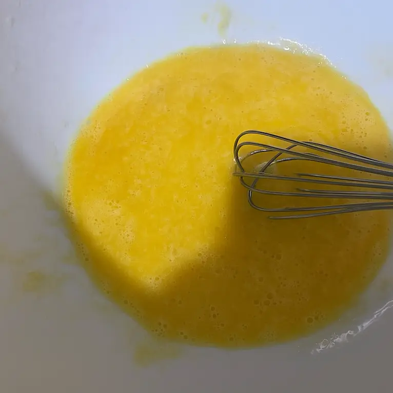 Beaten eggs in a bowl, ready for dipping prawns to help breadcrumbs stick and create a crispy golden finish