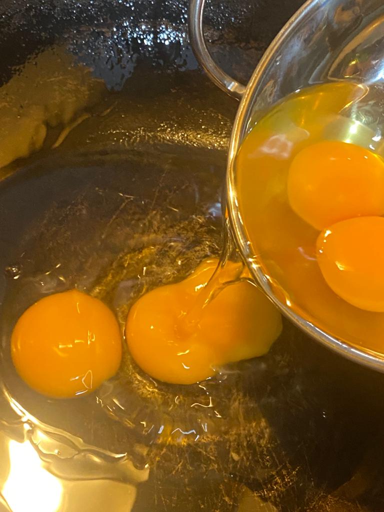 Cracking fresh eggs into a hot oiled pan