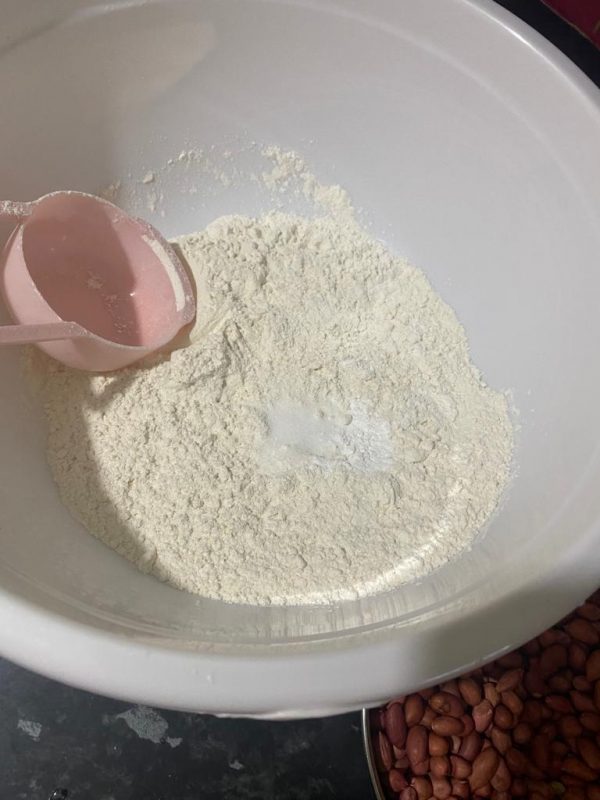 Bowl of flour with a pink measuring cup, ready to be mixed with spices for crispy chicken coating.