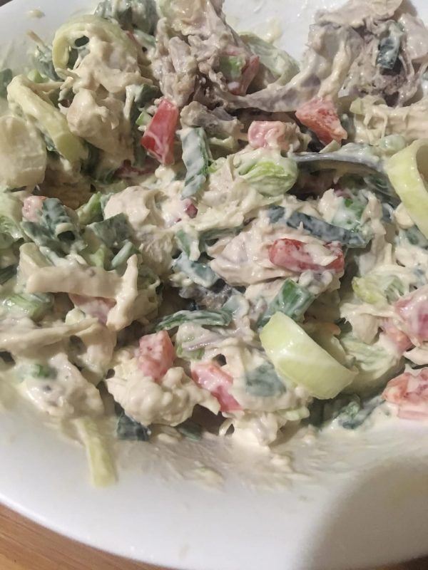 Bowl of creamy chicken salad mixed with vegetables like paprika, onion, and leek