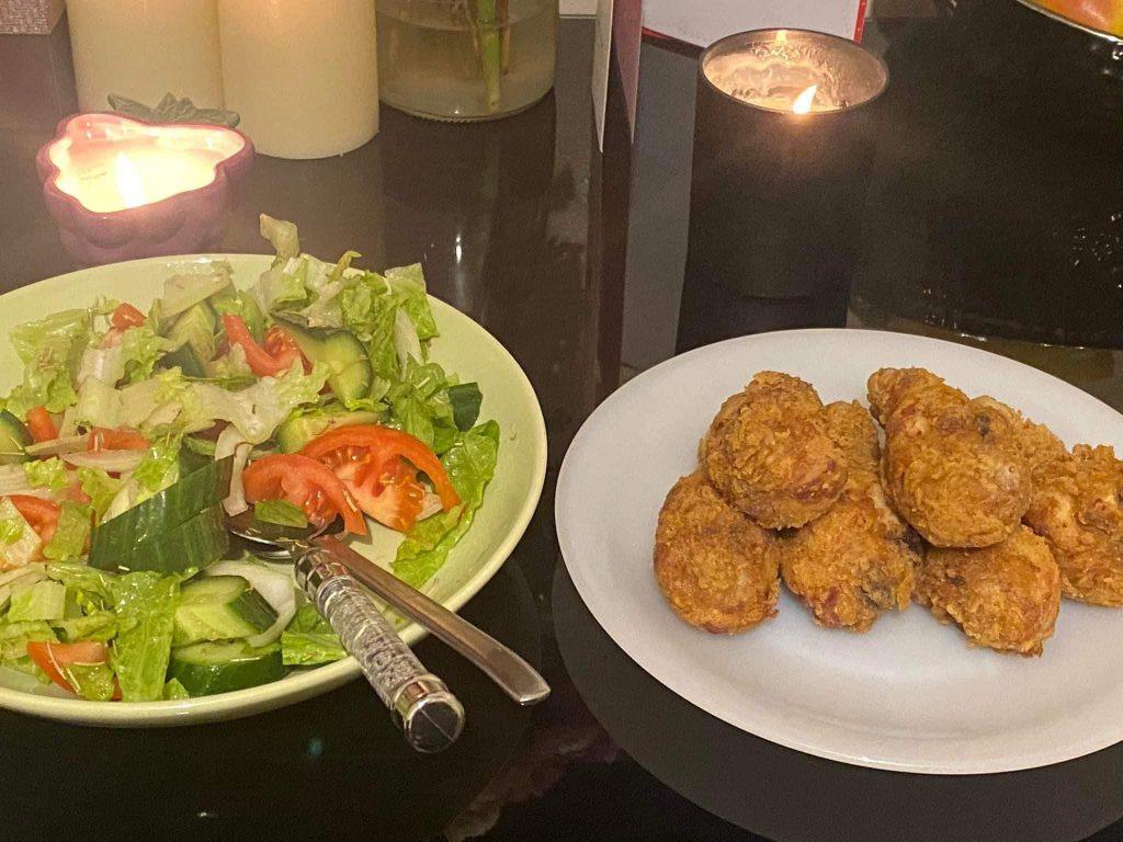 Crispy fried chicken served with a fresh green salad on a dinner table.
