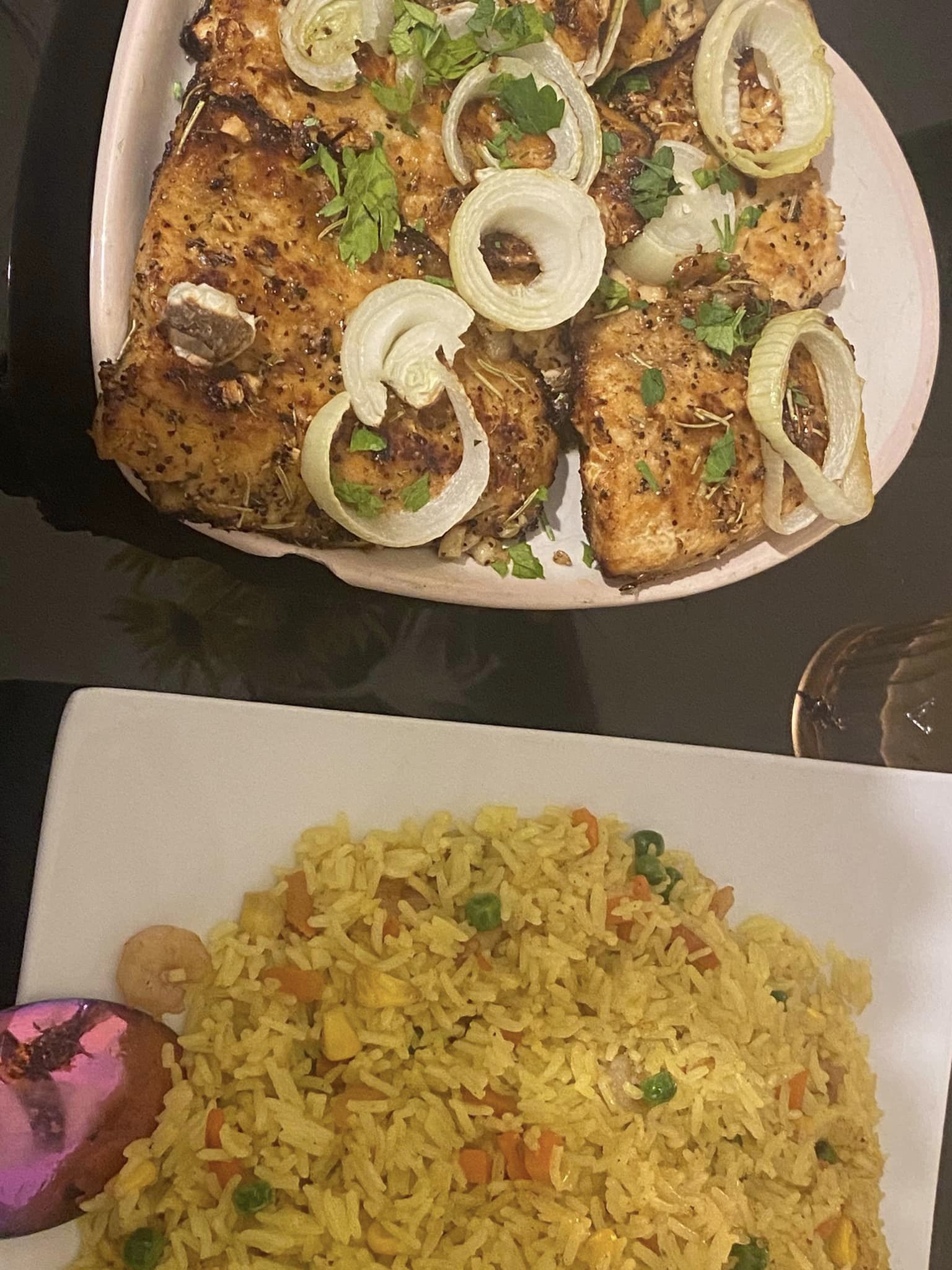 Grilled salmon fillets topped with onion rings and fresh herbs served with golden turmeric fried rice.