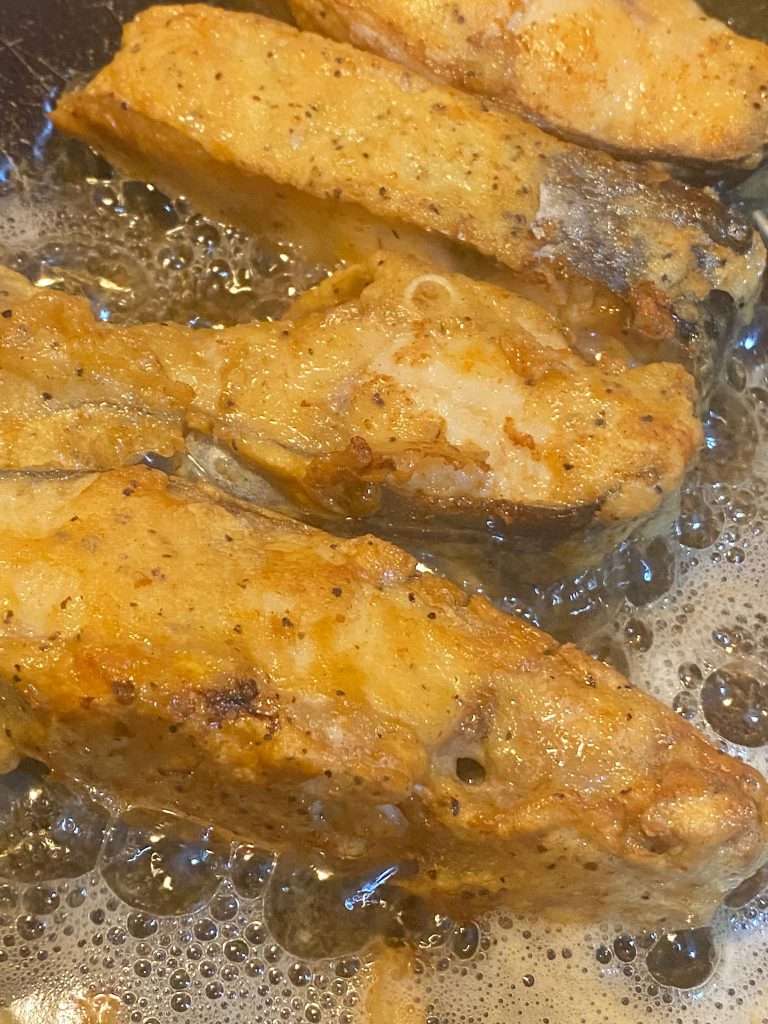 Golden-brown Pangasius steaks frying in hot oil.