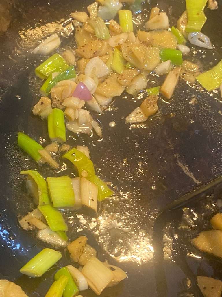 Fresh Pak Choi added to a stir-fry pan with colorful vegetables.