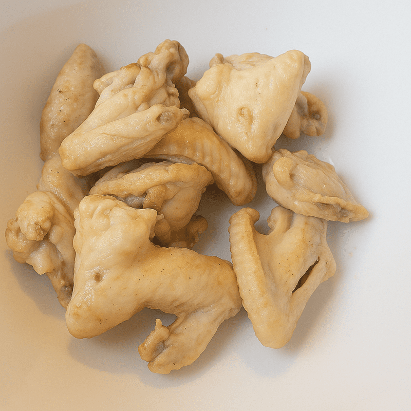 Golden-fried chicken wings resting on a plate after marination and frying.