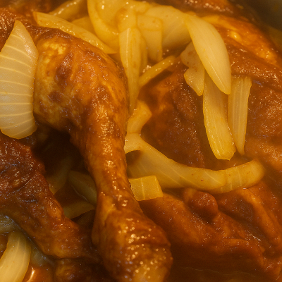 Fried chicken stir-fried with sliced onions in a pan.