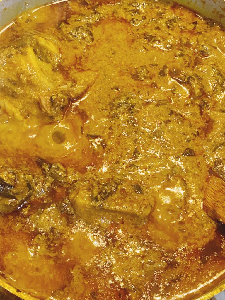 West African peanut soup simmering with tender meat and green potato leaves in palm oil.