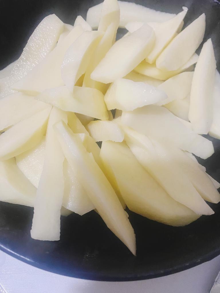 Raw potato wedges prepared for cooking, placed in a bowl.