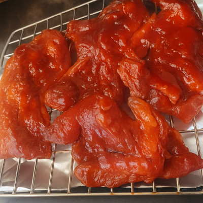 Marinated chicken pieces arranged on a wire rack ready for baking