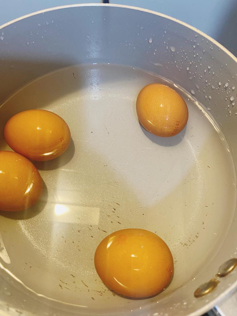 Four brown eggs are boiling in a saucepan filled with water