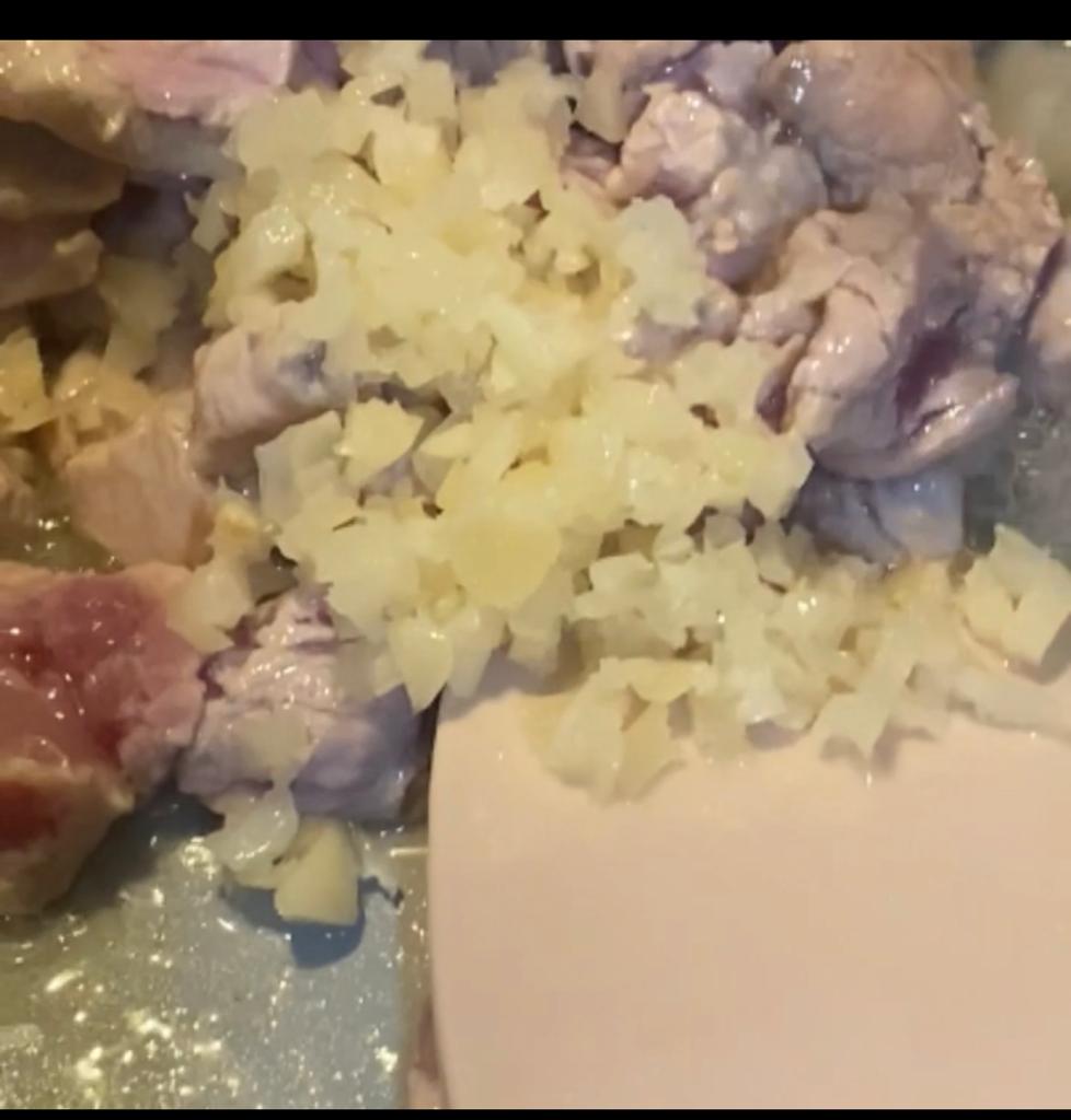 Minced garlic added to meat cooking in a skillet.