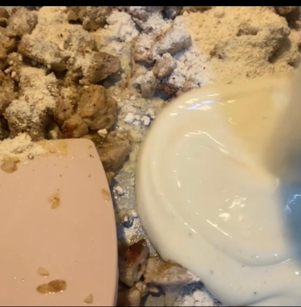 Mushroom sauce mixture being poured into a skillet with browned meat.