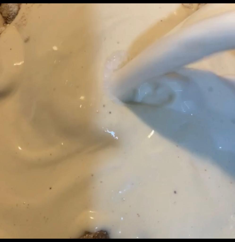 Pasta cream being poured into a skillet with mushroom sauce.