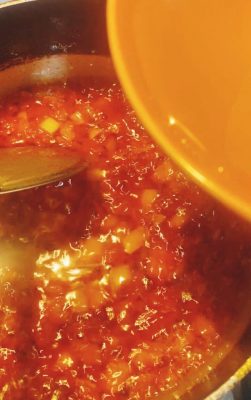 Simmering tomato sauce with onions and seasoning cube in a saucepan