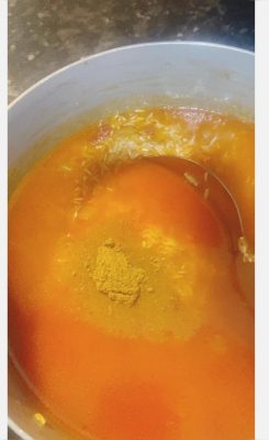 Rice cooking in tomato gravy with curry powder in a saucepan