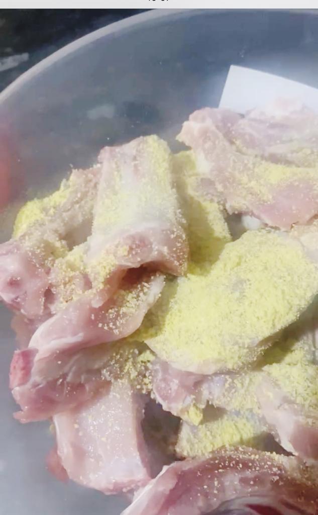Raw meat pieces in a bowl sprinkled with yellow Aromat seasoning