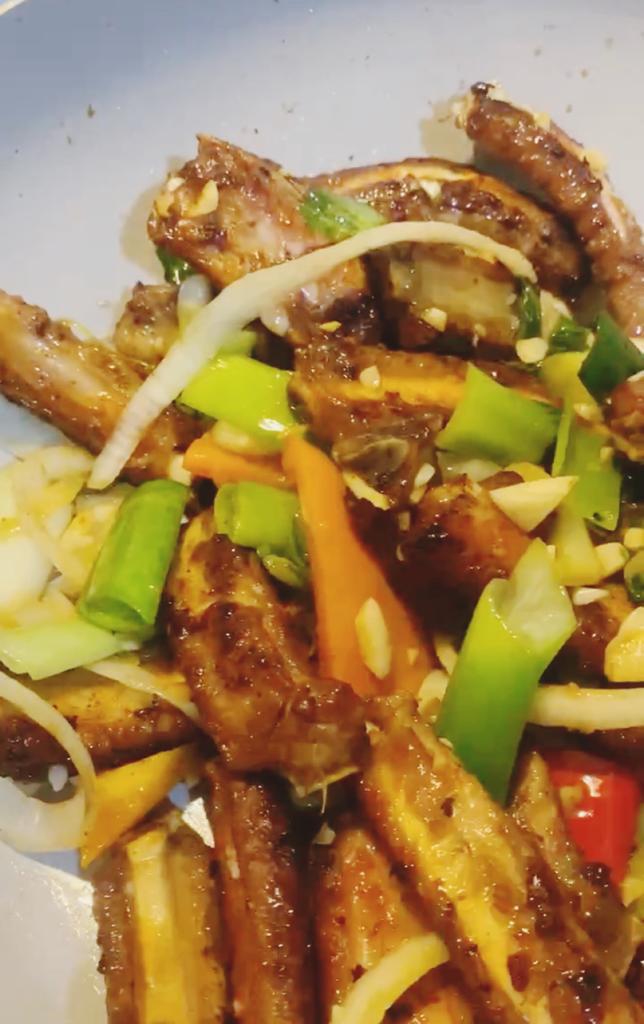 Cooked meat strips mixed with sautéed onions, peppers, and green vegetables in a pan