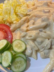 Creamy penne pasta garnished with fresh spring onions.