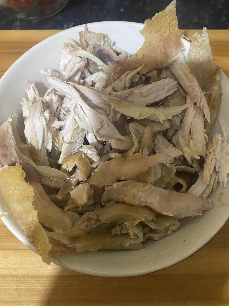 Chopped boiled chicken pieces on a white bowl ready for rice dish