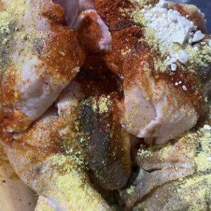 Raw chicken pieces marinated with paprika, garlic, seasoning, and oil.