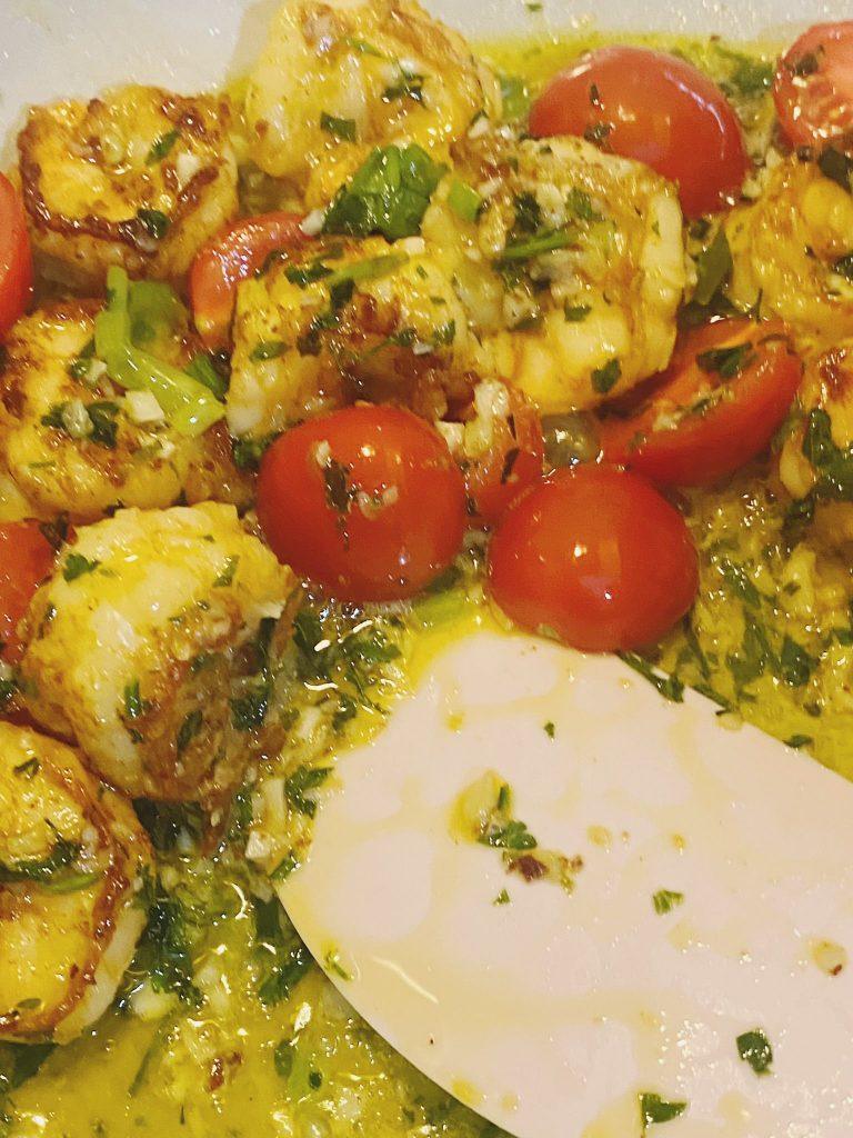 Prawns and tomatoes simmering in garlic butter sauce with herbs