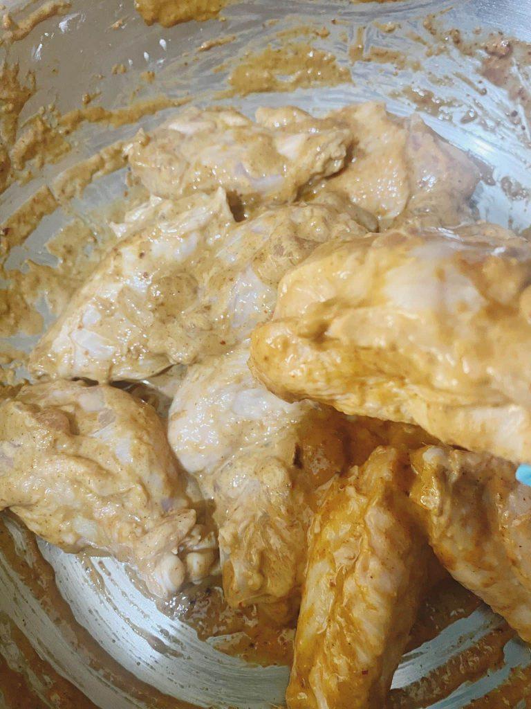 Marinated chicken wings coated with cornflour in a mixing bowl.
