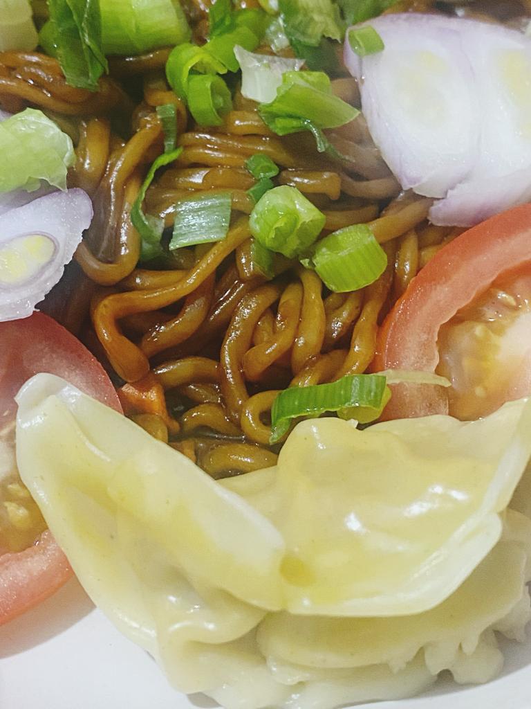 Close-up of vegetable dumplings served with noodles, eggs, and tomato garnish