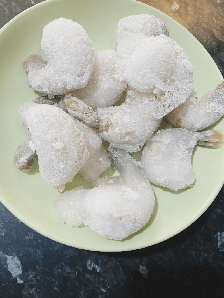 Raw jumbo prawns on a plate before cleaning and deveining
