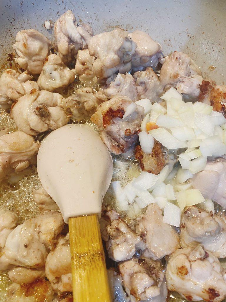 Golden chicken wings with sautéed onions and garlic in a pan