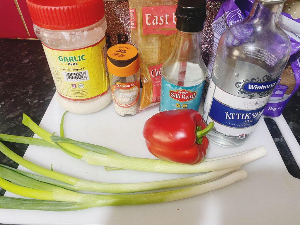 Fresh vegetables and seasonings for a gourmet vegetable medley, including spring onions, paprika, red pepper, and spices.
