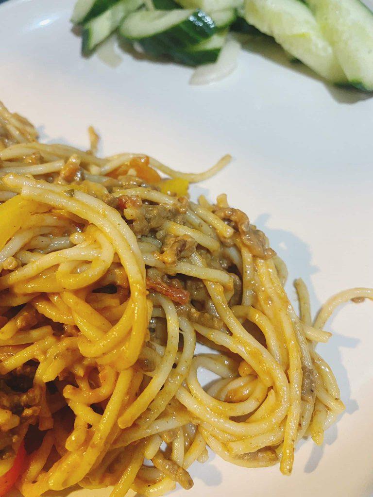 A serving of creamy beef spaghetti plated with a side of greens, ready to be enjoyed.