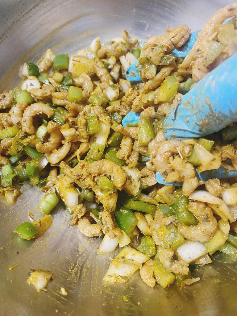 A hand mixing the pakora ingredients into a cohesive blend.