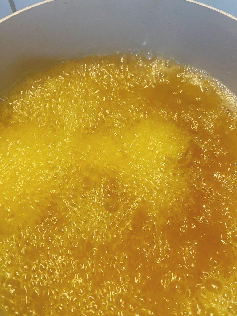 Hot cooking oil bubbling in a pan, ready for frying chicken pieces.