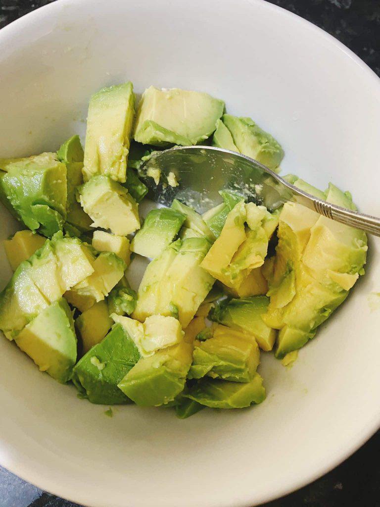 Cubed avocado in a bowl with a spoon before mashing