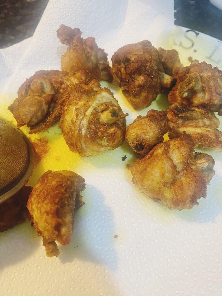 Crispy golden-brown chicken pieces resting on paper towels to drain excess oil after frying.