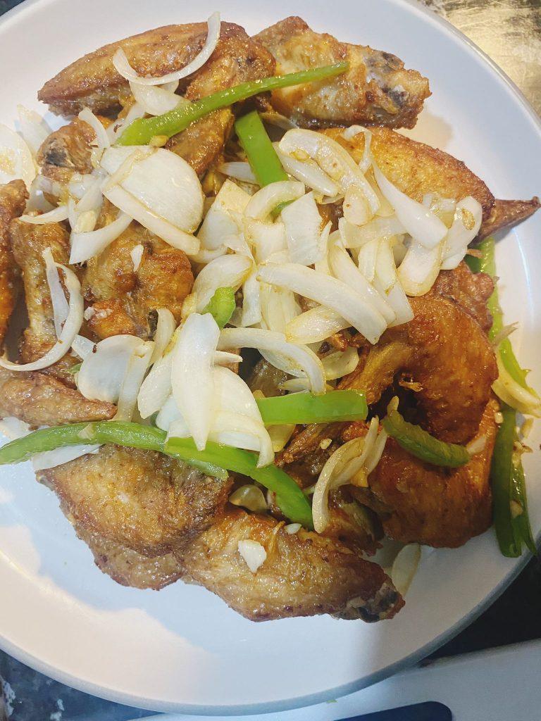 Crispy golden chicken wings served with stir-fried vegetables, ready to eat.