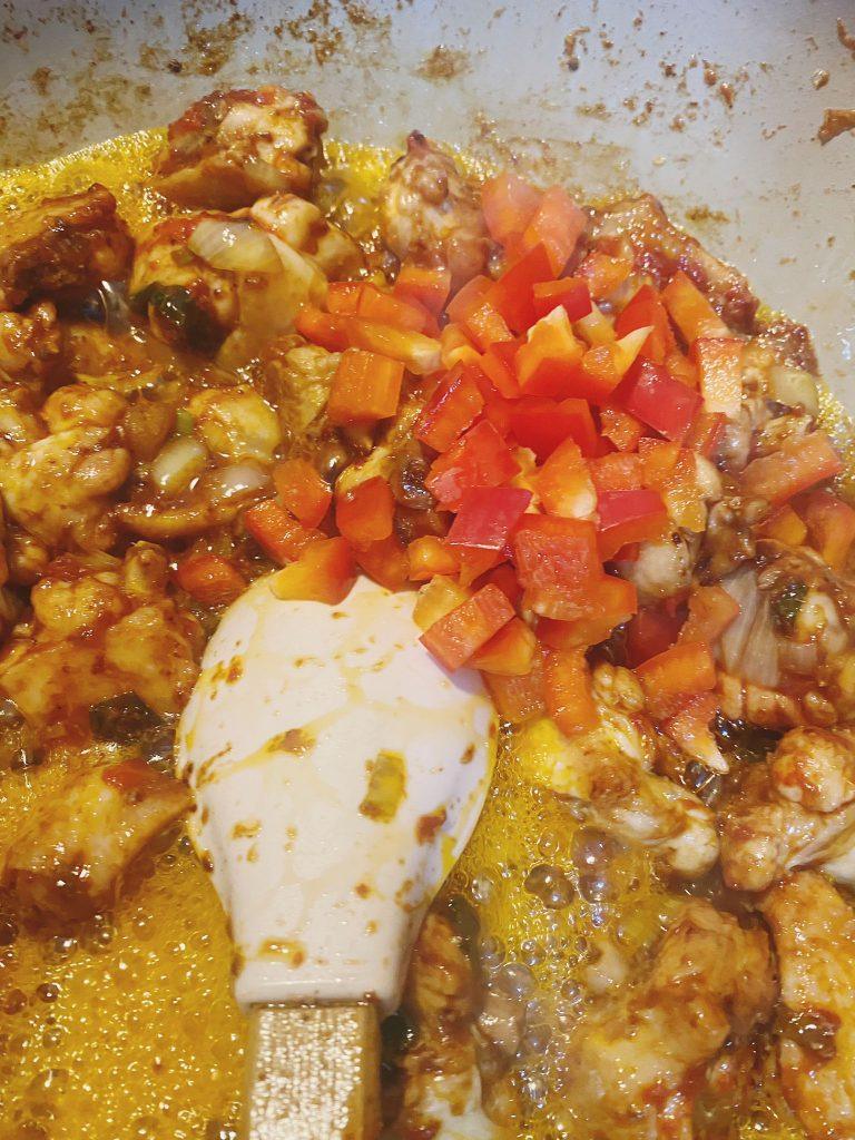 Stirring tomato paste and spices into chicken and onions