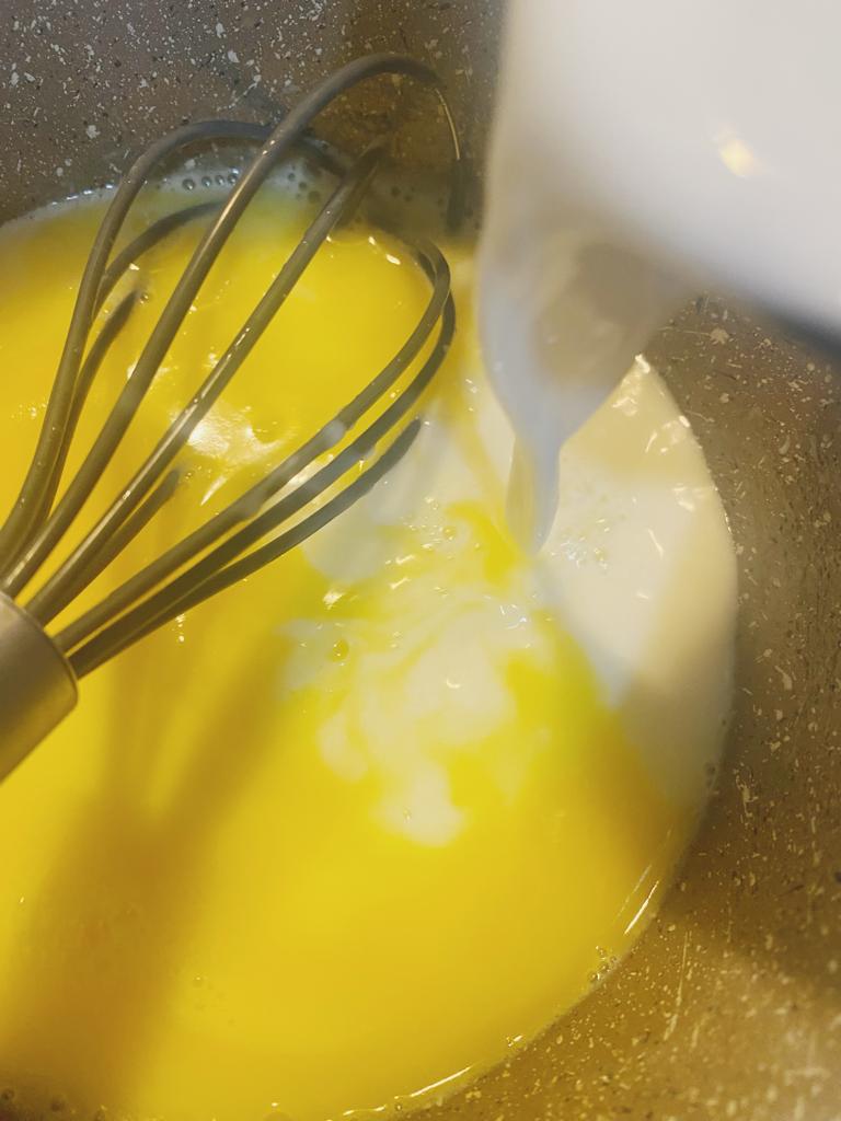 Milk being poured into melted butter with a whisk.