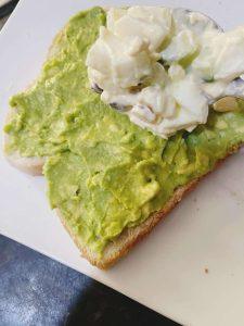 Avocado toast with creamy egg mixture being added on top