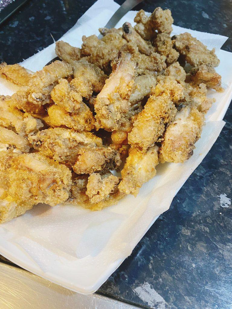 Golden fried chicken wings drained on paper towels.