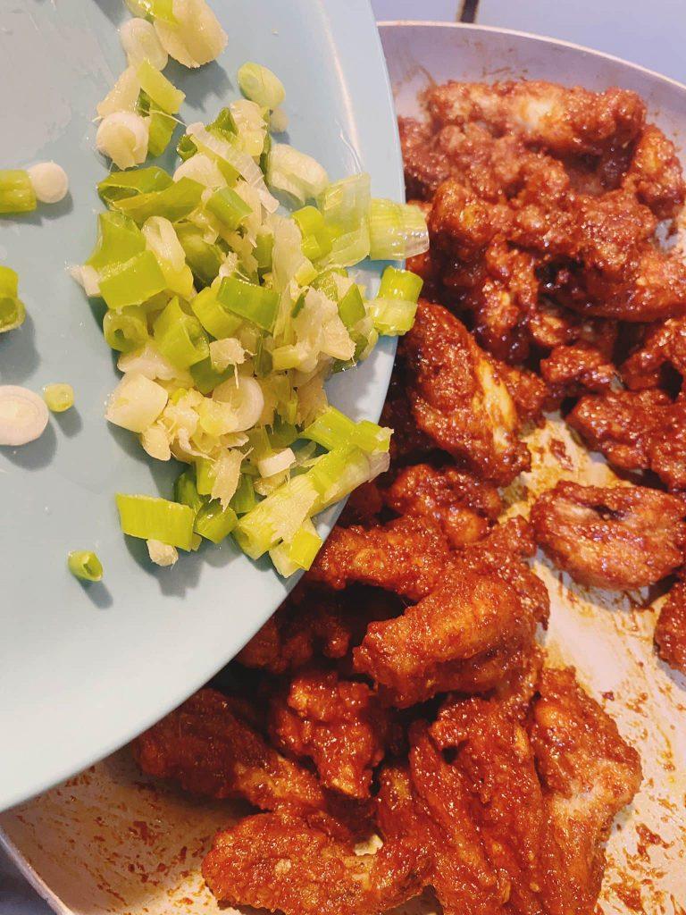 Chopped garlic and spring onions beside crispy cooked chicken, ready to be sautéed.