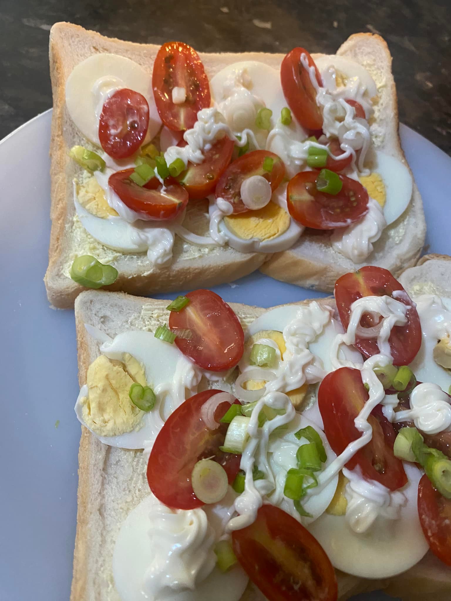 Golden egg and mayo sandwich in progress—layered with sliced eggs, mayonnaise, juicy tomatoes, and a sprinkle of chopped spring onions on buttered bread.