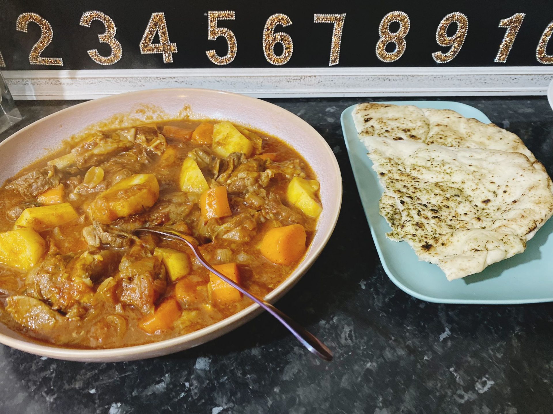 Bowl of hearty vegetable soup served with naan bread on the side