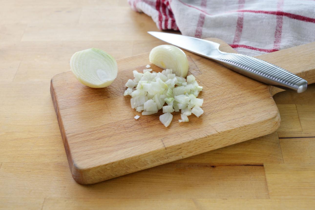 Finely chopped white onion cubes on cutting board for sandwich recipe