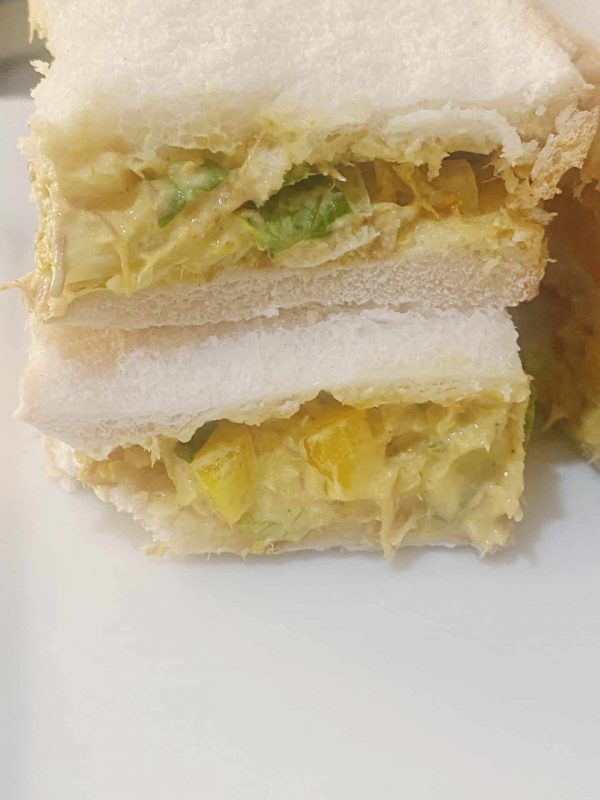 Close up of creamy mackerel rillettes sandwich showing filling with vegetables inside soft bread