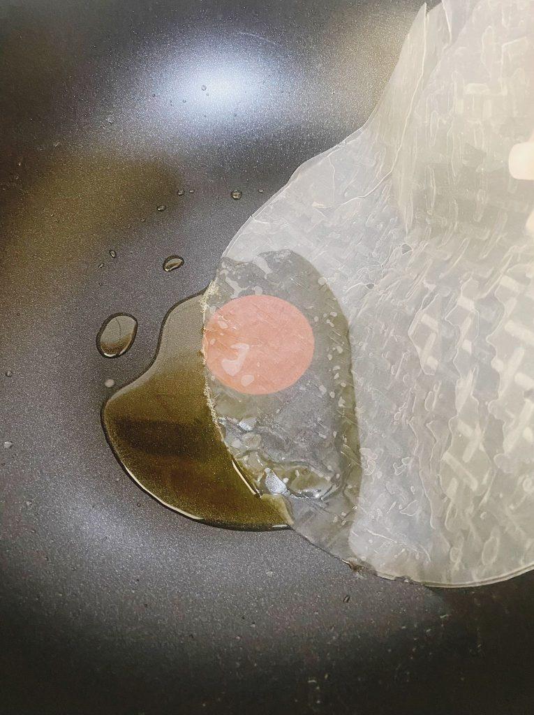 Rice paper sheets being soaked in warm water, preparing them for frying by making them pliable.