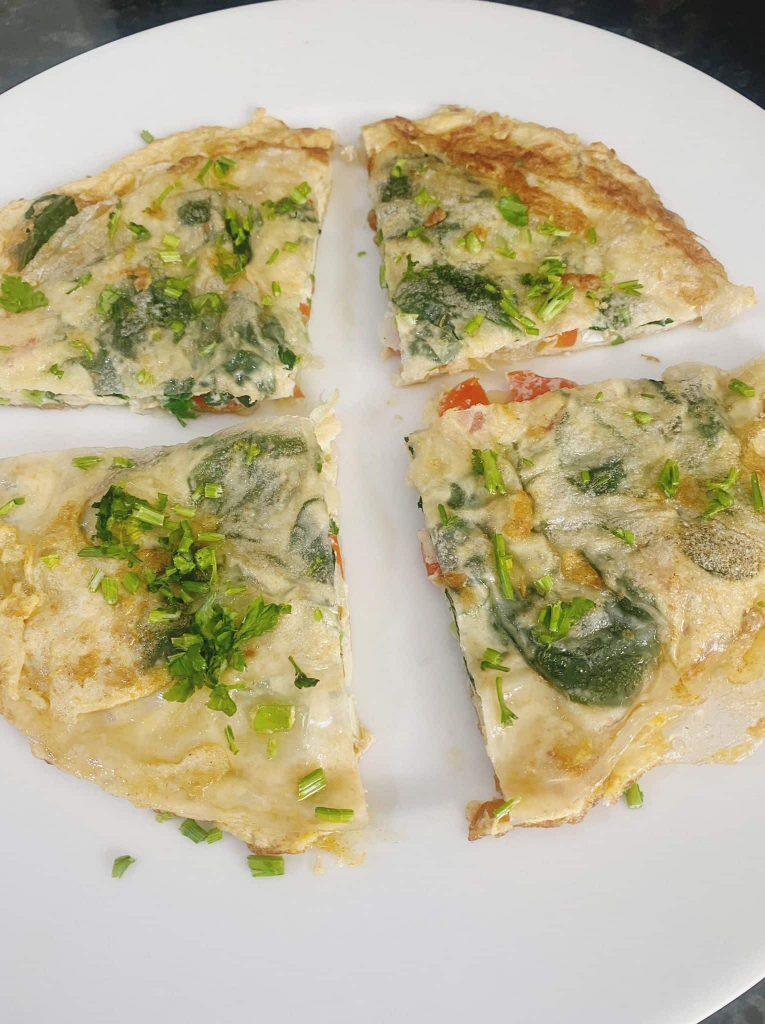 Omelet sliced into four quarters and garnished with parsley, served with mayonnaise and ketchup on the side.