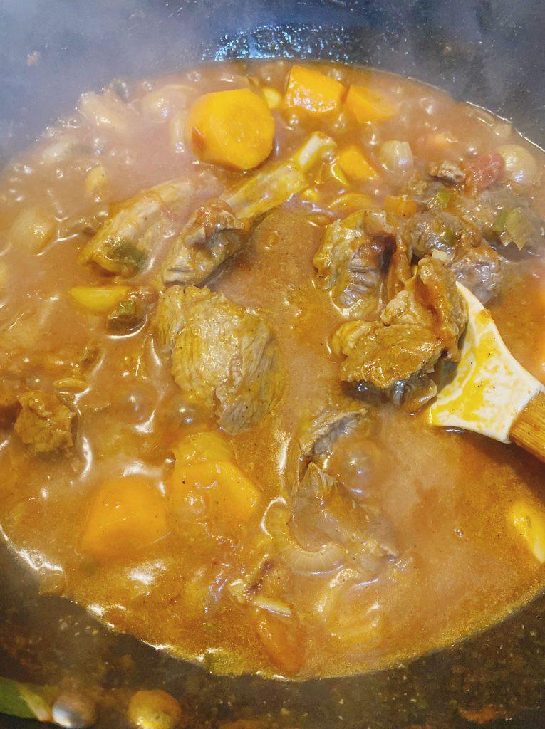 A bubbling pot of rich, thickened soup with tender meat and soft vegetables.