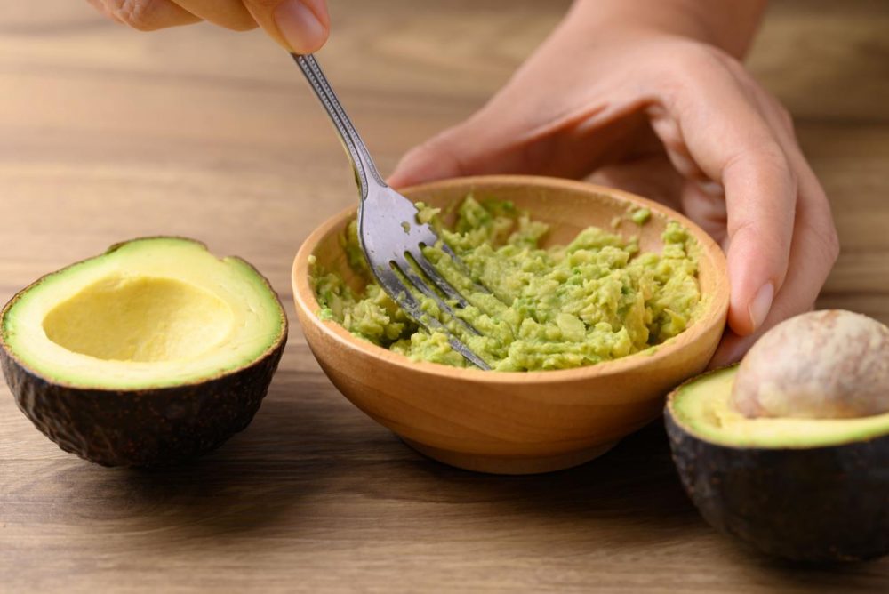 Mashing avocado with a fork in a bowl for creamy texture