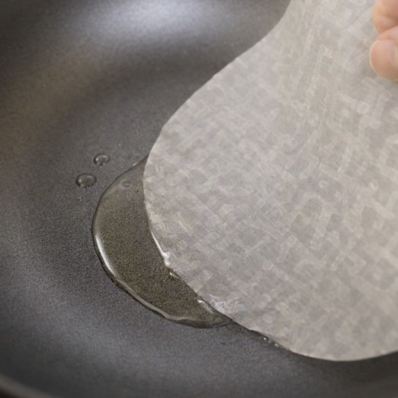 Rice paper sheet placed in a frying pan with oil ready for omelette base